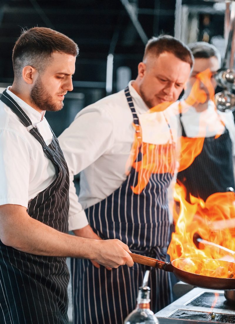 flaming-the-meal-on-frying-pan-kitchen-workers-is-together-preparing-the-food.jpg